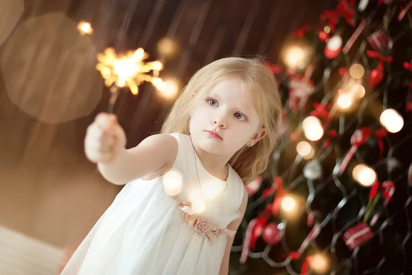 Firewors 坚持圣诞树背景的小女孩 — 图库照片