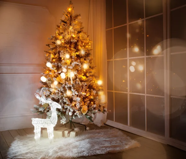 Un árbol de Navidad iluminado con regalos debajo en la sala de estar — Foto de Stock