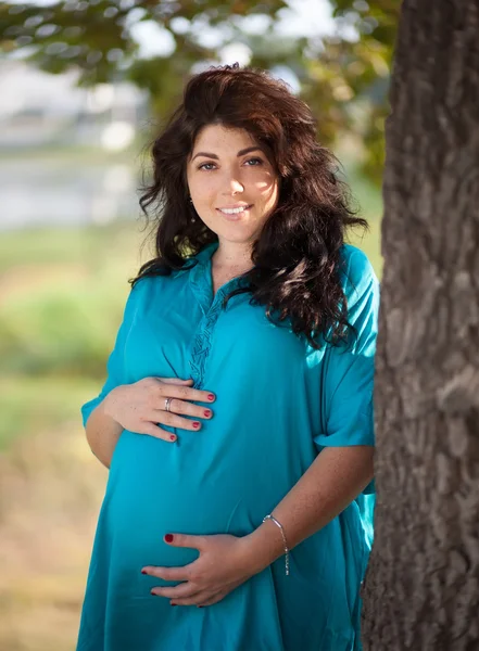 Mooie zwangere vrouw in een turquoise jurk buiten — Stockfoto