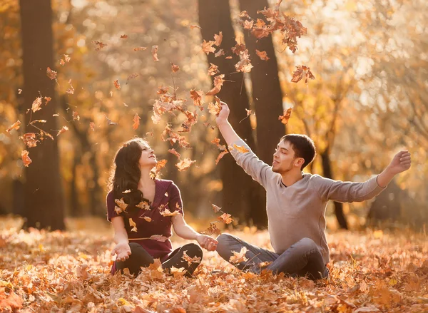 Couple throwing leaves and having fun in autumn park — Stock Photo, Image