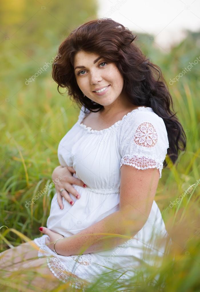 Beautiful pregnant woman in wite dress outside