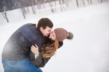 Kış orman aşık genç bir çift. Genç adam kızı kucaklar. Gülüyor.