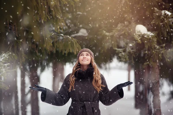 Unga vackra kvinnan i parken har snöfall — Stockfoto