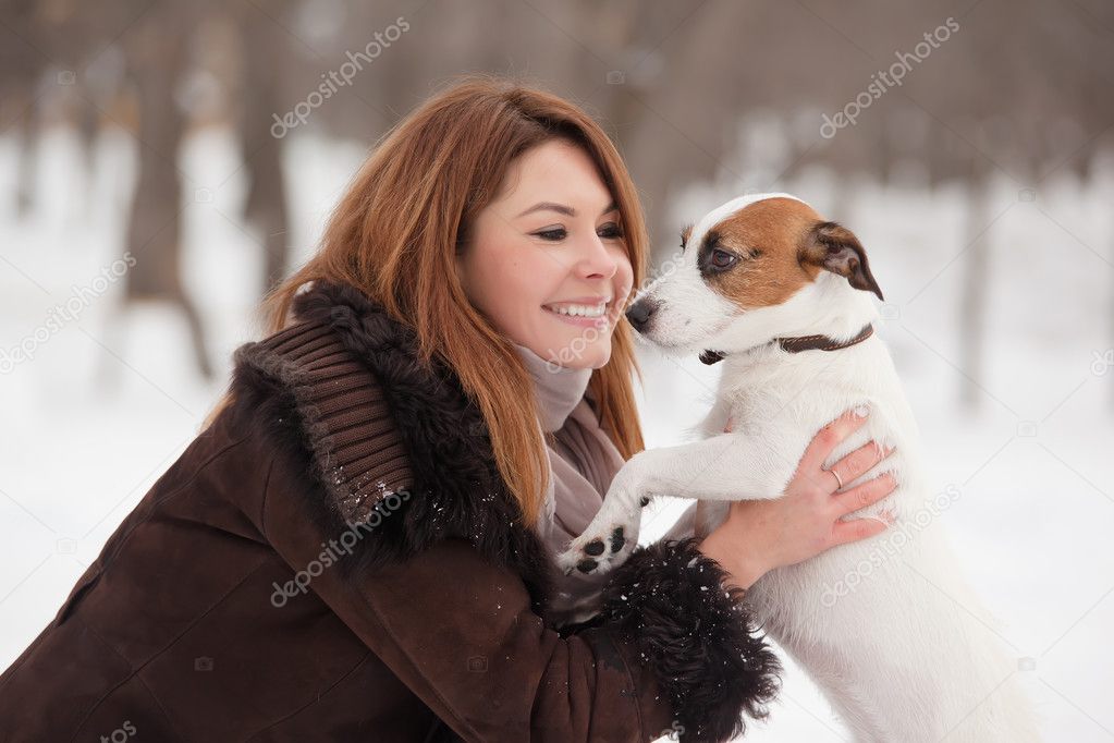 Young redhead woman outdoors with cute dog - Jack Russell Terrier, winter season.