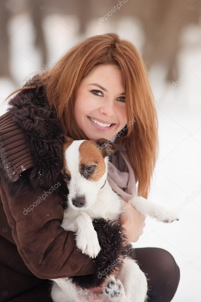 Young redhead woman outdoors with cute dog - Jack Russell Terrier, winter season.