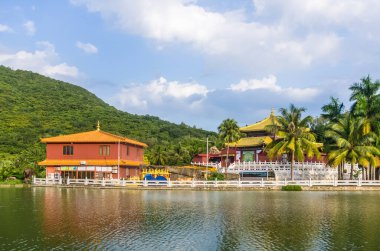 SANA, HAINAN, ÇİN - 10 Ekim 2019 'da Sanya Nanshan Kültür Merkezi' ndeki gölet kıyısında geleneksel Çin mimarisinin renkli bir geçidi, Sanya, Hainan, Çin