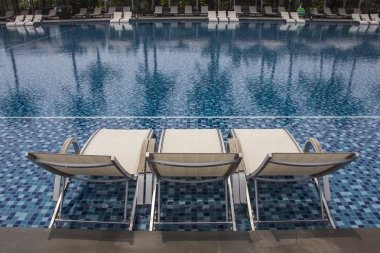 Lüks Yüzme Havuzu ve mavi su Resort havuzlu güzel lüks sandalye üstünde onun taraf ve yansımaları ve palmiye ağaçlarının