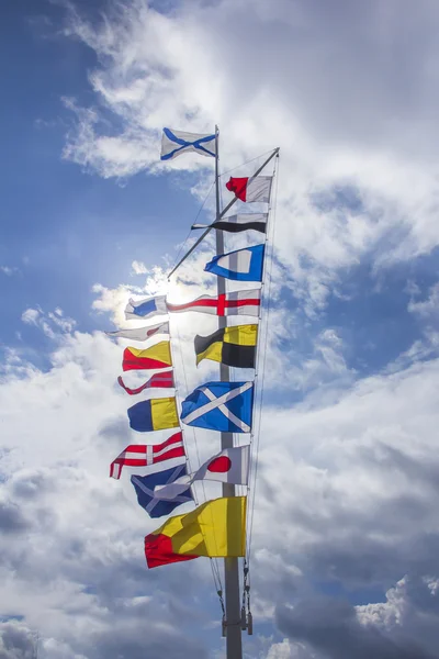 Міжнародні морські сигнальні прапори на флагштоку на фоні блакитного неба — стокове фото