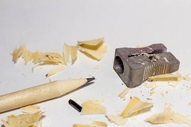 Metal bileyicili kırık kalem, kırık kurşun çubuk ve beyaz kağıtta talaş.