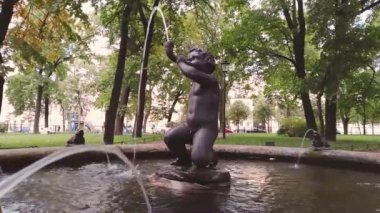 Çeşmelerden birinin manzarası. Küçük bir çocuk, Aşk Tanrısı Nikolskiy bahçesinde korna çalıyor. Saint-Petersburg, Rusya 'daki St. Nicholas Donanma Katedrali yakınlarında.