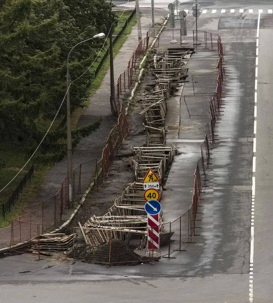 Bajo señales de carretera de reconstrucción en una calle con trinchera excavada —  Fotos de Stock