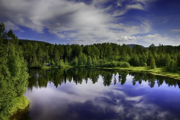 Rustig lake reflectie tegen de blauwe hemel met witte wolken — Stockfoto