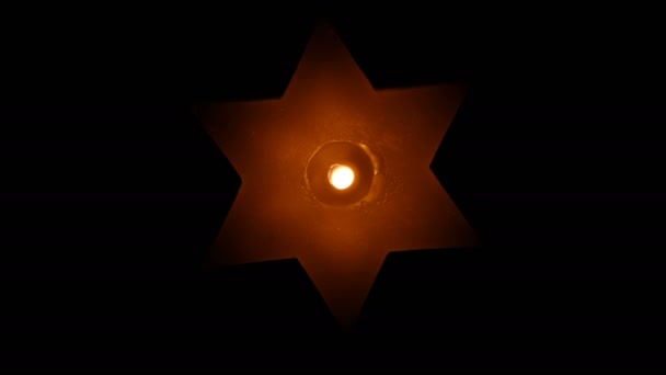 大卫六角星形状的一支纪念蜡烛正在燃烧 并在一个4K分辨率视频剪辑的黑色背景上旋转着 — 图库视频影像