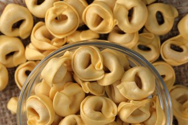 Çiğ tortellini peynirli geleneksel İtalyan hamur tatlısı masanın üzerinde yakın plan makro fotoğrafçılık yatıyor.