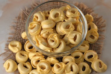 Çiğ tortellini peynirli geleneksel İtalyan hamur tatlısı masanın üzerinde yakın plan makro fotoğrafçılık yatıyor.