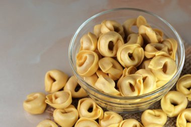 Çiğ tortellini peynirli geleneksel İtalyan hamur tatlısı masanın üzerinde yakın plan makro fotoğrafçılık yatıyor.