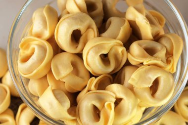 Çiğ tortellini peynirli geleneksel İtalyan hamur tatlısı masanın üzerinde yakın plan makro fotoğrafçılık yatıyor.