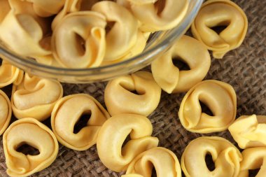 Çiğ tortellini peynirli geleneksel İtalyan hamur tatlısı masanın üzerinde yakın plan makro fotoğrafçılık yatıyor.