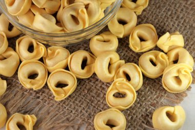 Çiğ tortellini peynirli geleneksel İtalyan hamur tatlısı masanın üzerinde yakın plan makro fotoğrafçılık yatıyor.