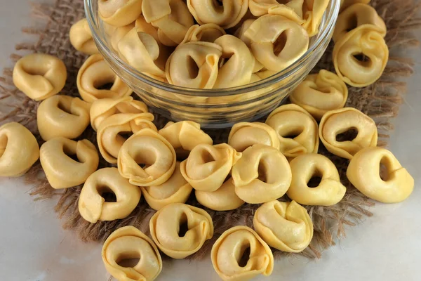 Çiğ tortellini peynirli geleneksel İtalyan hamur tatlısı masanın üzerinde yakın plan makro fotoğrafçılık yatıyor.