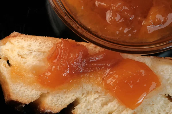 Een Schijfje Witte Broodjes Met Perzikjam Ligt Een Zwarte Achtergrond — Stockfoto