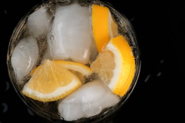 Limonata, limon ve buz dilimleri ile şeffaf kristal cam yakın çekim makro fotoğraf.