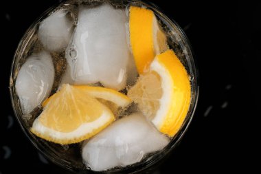 Limonata, limon ve buz dilimleri ile şeffaf kristal cam yakın çekim makro fotoğraf.