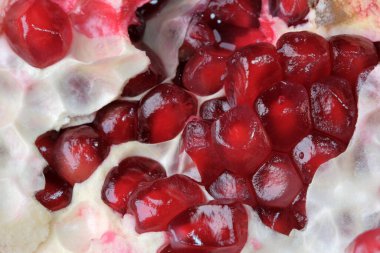 Olgunlaşmış kırmızı, tatlı, soyulmuş nar cam bir vazonun üzerinde yatıyor. Yakın plan makro fotoğraf.