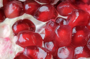 Olgunlaşmış kırmızı, tatlı, soyulmuş nar cam bir vazonun üzerinde yatıyor. Yakın plan makro fotoğraf.