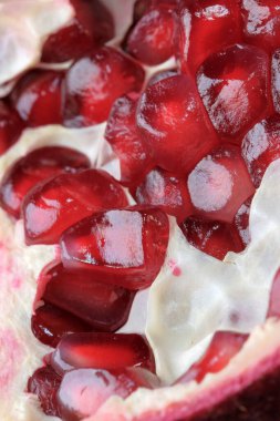 Olgunlaşmış kırmızı, tatlı, soyulmuş nar cam bir vazonun üzerinde yatıyor. Yakın plan makro fotoğraf.