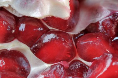 Olgunlaşmış kırmızı, tatlı, soyulmuş nar cam bir vazonun üzerinde yatıyor. Yakın plan makro fotoğraf.