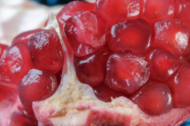 Olgunlaşmış kırmızı, tatlı, soyulmuş nar cam bir vazonun üzerinde yatıyor. Yakın plan makro fotoğraf.