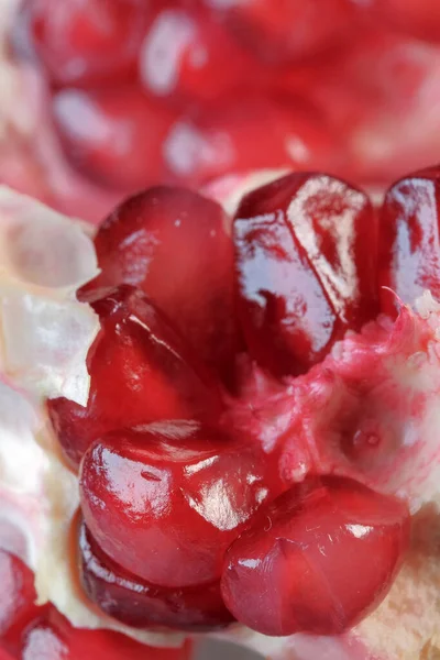 Olgunlaşmış kırmızı, tatlı, soyulmuş nar cam bir vazonun üzerinde yatıyor. Yakın plan makro fotoğraf.