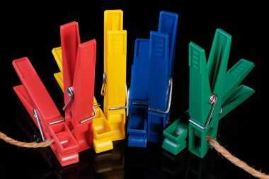 Siyah aynalı arkaplanda, çamaşır mandalları yakın çekim makro fotoğrafçılığıyla renkli kompozisyon