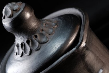 Servis kapaklı bir sürahi, siyah arka planda siyah kilden yapılmış tabaklar yakın plan makro fotoğraf.