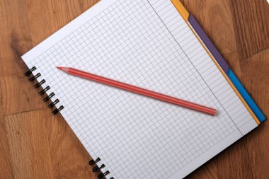 Tahta bir arka plan üzerinde kırmızı bir kalem ile kare kağıtlar için yırtık not defterini aç