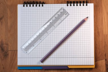 Saydam cetvel ve kurşun kalemle kareli sayfaların olduğu bir not defterinin kırtasiye bileşimi