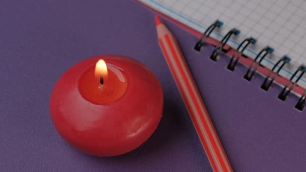 Kleine Rote Runde Kerze Brennt Neben Einem Notizbuch Nahaufnahme Video — Stockvideo