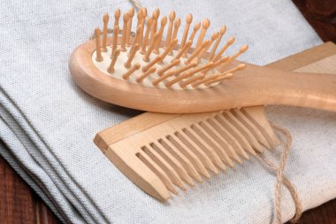 Ahşap masaj tarakları keten peçeteye, koyu ahşap arka plan saç bakım aletlerine yakın.