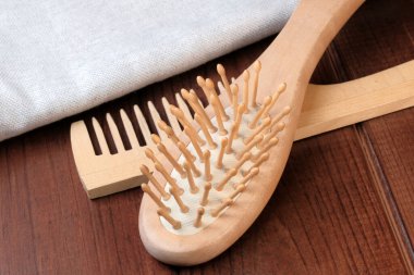 Tahta masaj tarakları keten peçetenin yanında. Koyu ahşap arka plan saç bakım aletlerine yakın.