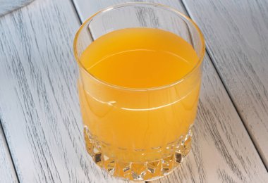 Açık ahşap arka planda bir bardakta portakal suyu yakın plan makro fotoğraf.