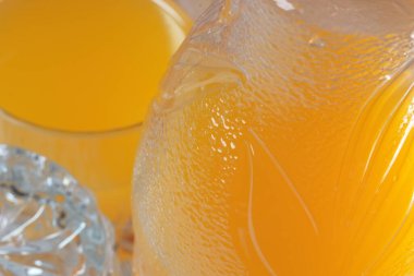 Plastik şişede portakal suyu ve hafif ahşap arka planda cam yakın plan makro fotoğraf.