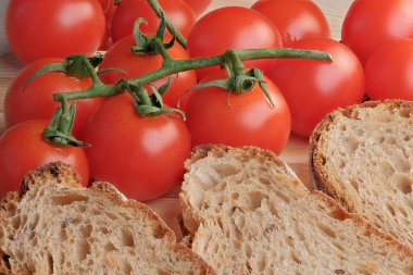 Dal üzerinde küçük domatesler, dilimlenmiş tahıl ekmeğinin yanında uzanıyor. Yakın çekim makro fotoğraf.