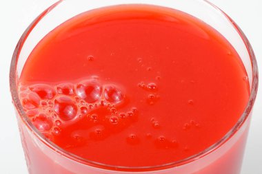 Kalın bir bardakta posası olan kalın domates suyu yakın plan beyaz bir fonda.