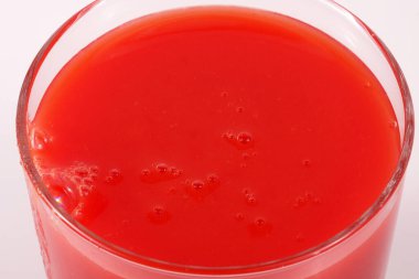 Kalın bir bardakta posası olan kalın domates suyu yakın plan beyaz bir fonda.