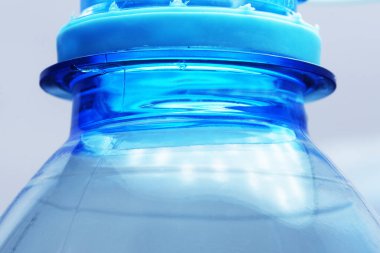 Mavi plastik şişenin arka plan boynu ve içme suyu yakın çekim makro fotoğrafçılığı.