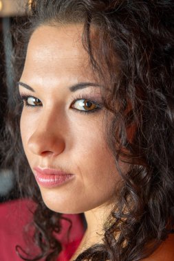 Esmer, kıvırcık saçlı, siyah saçlı, Asya görünümlü çekici bir kızın portresi.