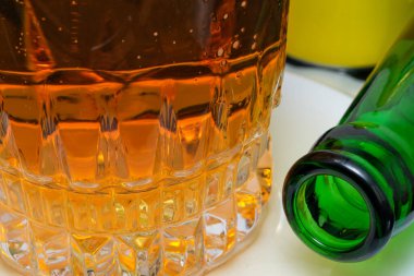 Taze soğuk bira bardağa doldurulur boş yeşil bir şişenin yanına yakın çekim makro fotoğraf.