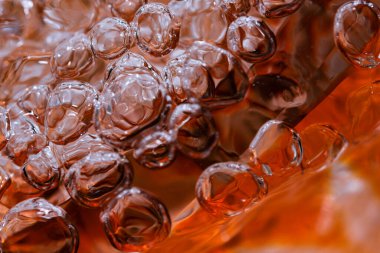 Güçlü bir deredeki soyut makro fotoğraf suyu kırmızı bir vazoyu hava kabarcıklarının oluşumuyla doldurur.