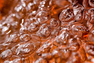 Güçlü bir deredeki soyut makro fotoğraf suyu kırmızı bir vazoyu hava kabarcıklarının oluşumuyla doldurur.